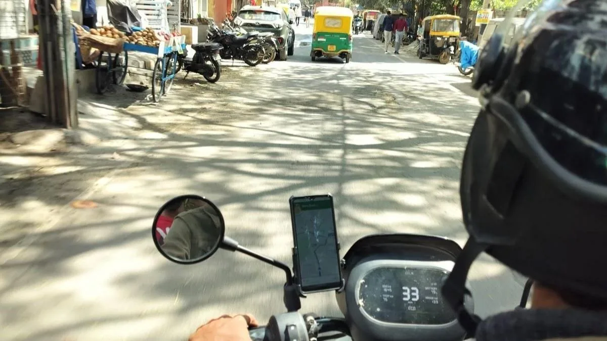 A rider’s view over the handlebar of a scooter, a phone in its mount showing a map